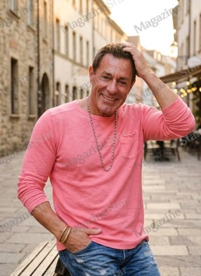 Actor and Mulberry Street Pizzeria owner Richie Palmer smiling in a pink shirt.