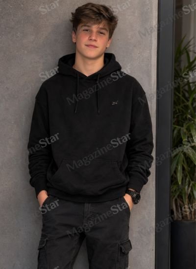 Leonard Sandler, son of Kathryn Hahn and Ethan Sandler, posing in a black hoodie.