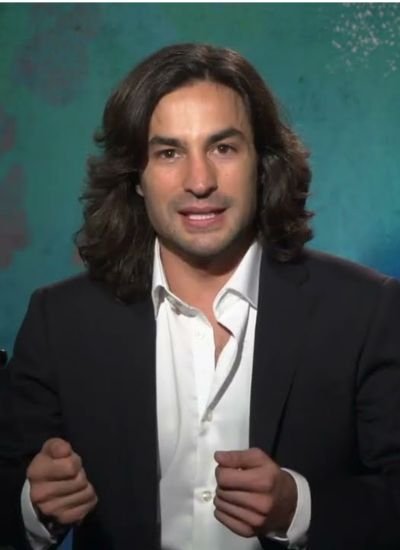 Marvel Studios executive producer Richie Palmer speaking in an interview, wearing a black blazer and white shirt.